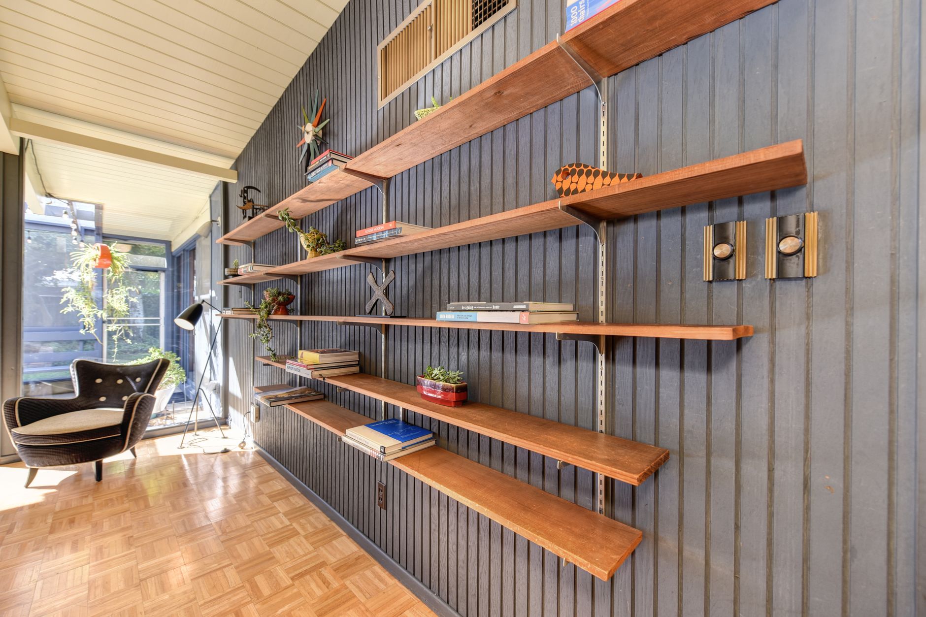 Walnut wall shelves along ribbed panel wall with parquet floor