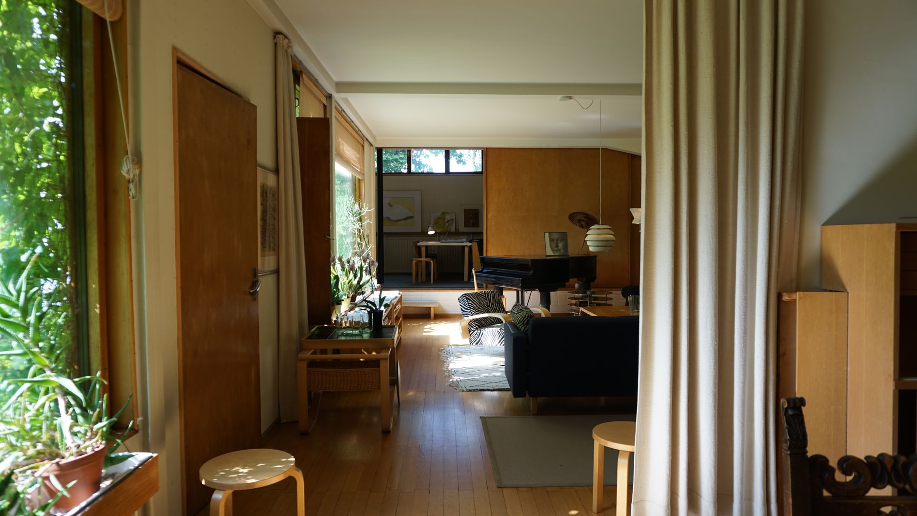 Plywood-paneled open living room with band windows and warm wood floors
