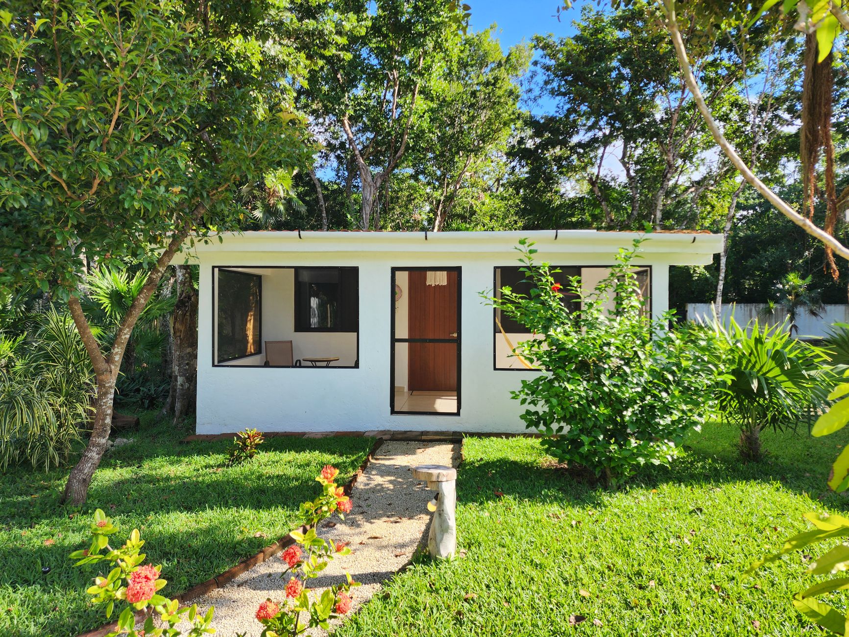A small white house surrounded by lush greenery in a serene garden setting, perfect for peaceful living.