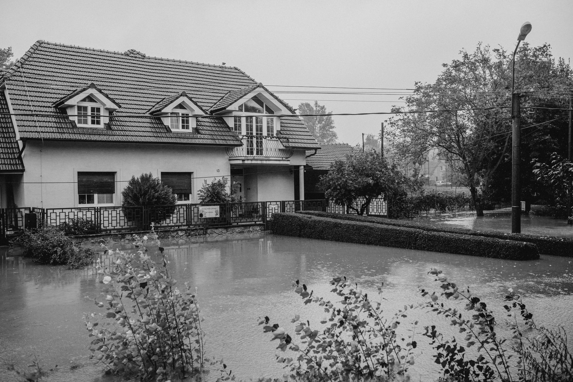 Black and white image of a flooded home surrounded by rising water.