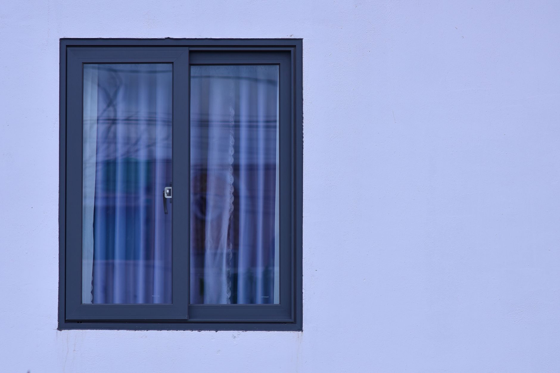 A minimalist view of a modern window with frosted glass on a light blue wall.