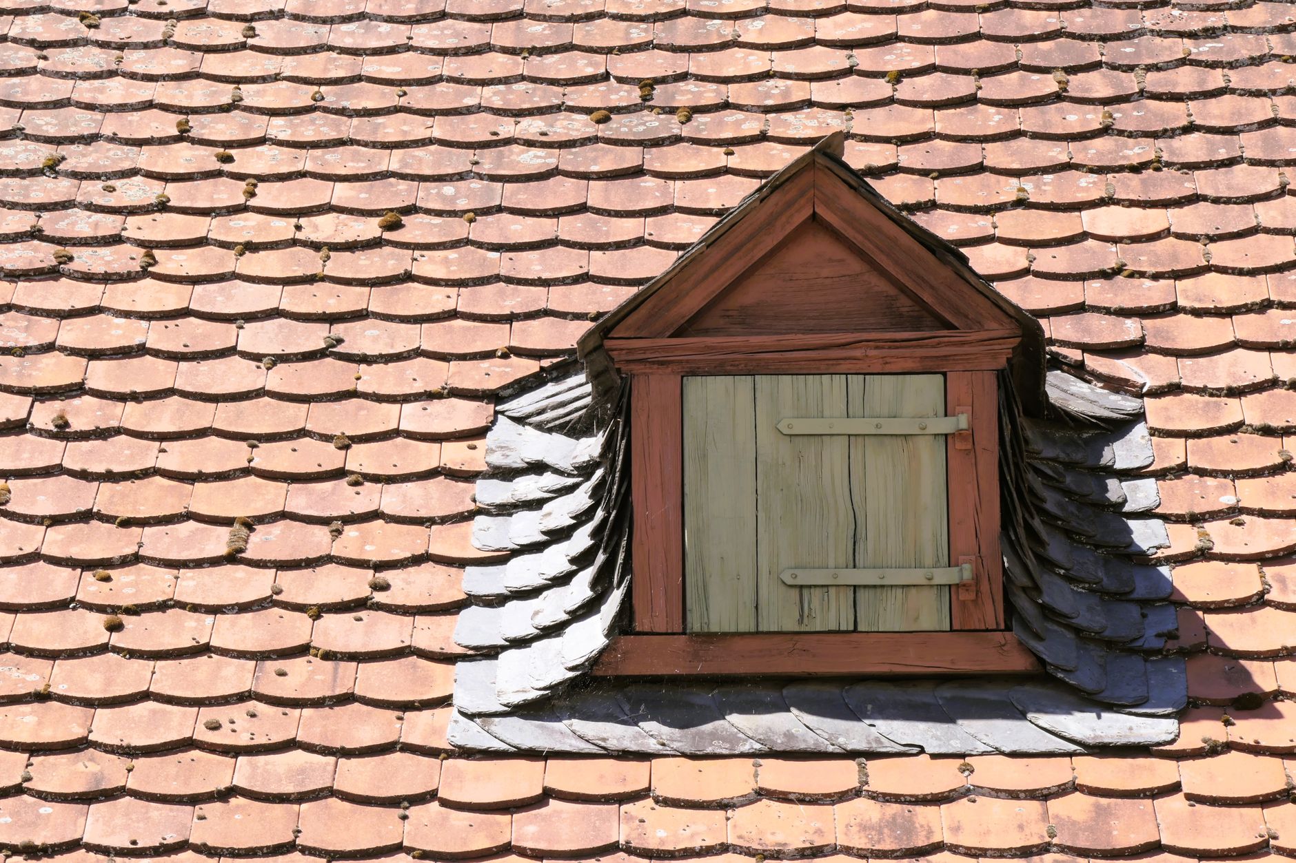 Charming dormer window on a vintage shingled roof, offering an architectural close-up.