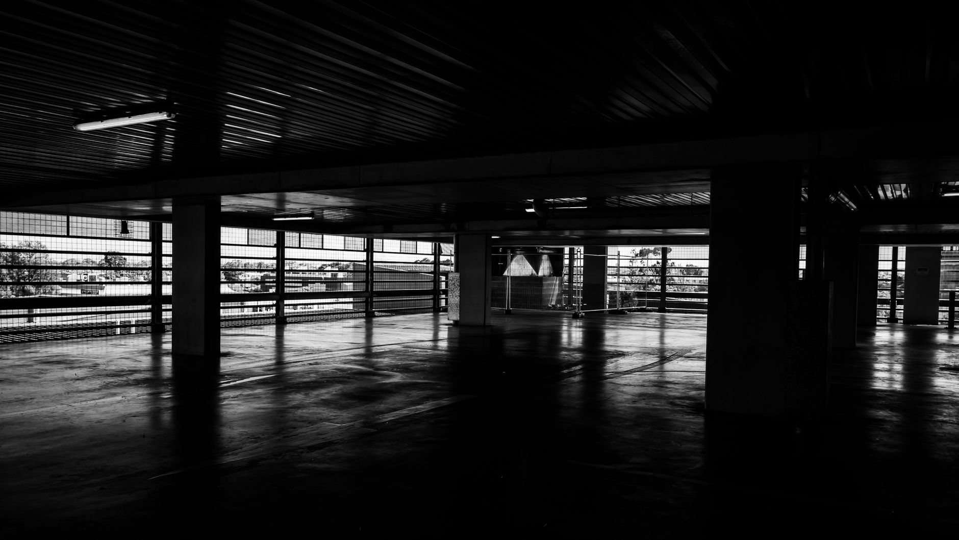 Moody black and white depiction of an empty urban multi-story parking garage.