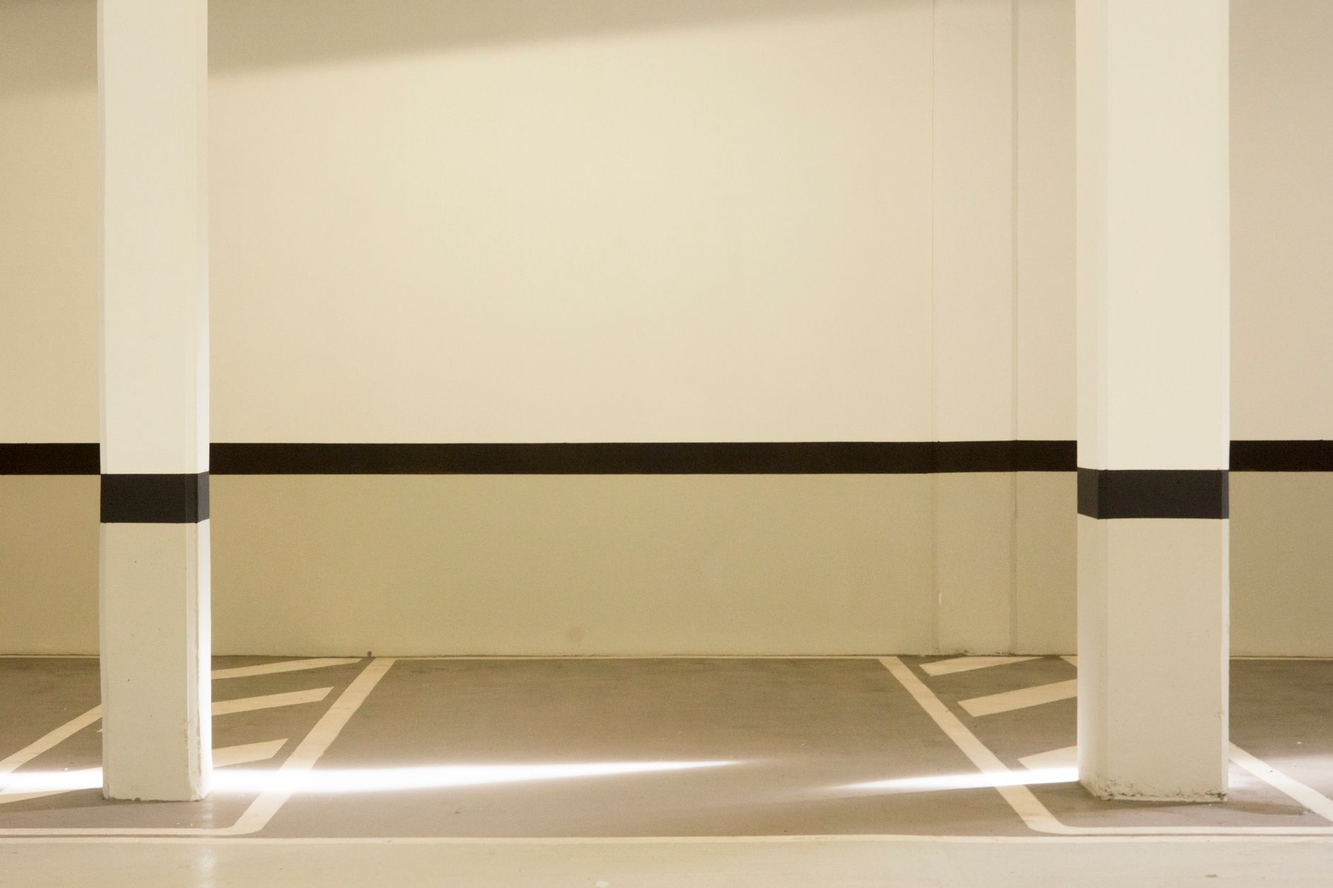 A minimalist view of a well-lit, empty parking garage interior featuring structural posts.